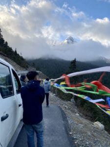 色季拉山口路邊經幡、白色車輛與雲霧中的雪峰,魯朗林海與南迦巴瓦觀景路線